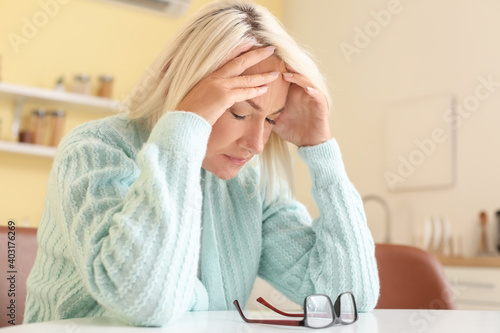 Stressed mature woman suffering from headache at home