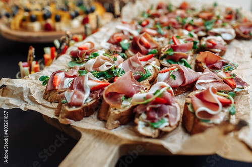 Festive Buffet. An assortment of cold cuts and canapes on wooden skewers. Cocktail reception at the party. catering with meats, fruits, cheeses and sandwiches.