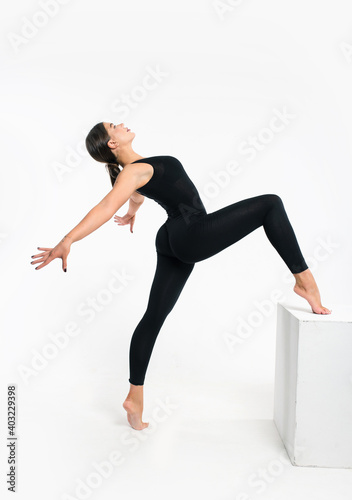 Athletic flexibility woman gymnast in sportswear performs gymnastics fitness exercises on white background. Sports motivation, stretching