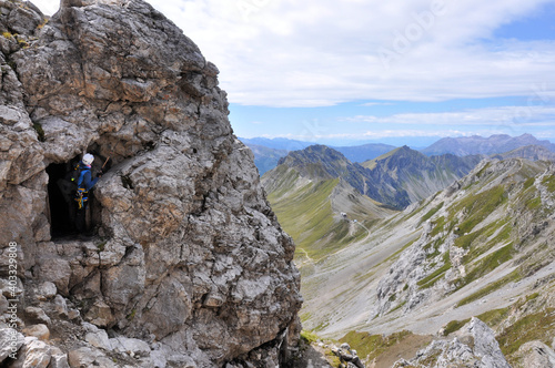 Męzczyzna podziwia górskie widoki z okna wydrążonego w skale, Dolomity