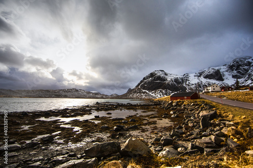 Beautiful landscape. Lofoten Islands. Stones, a red house against the backdrop of mountains and clouds.