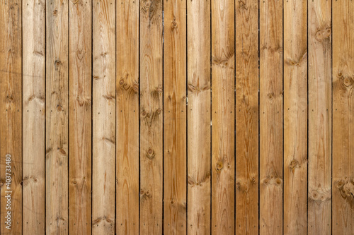 Full frame texture background of a wooden fence with natural wood grain planks, in bright sunlight