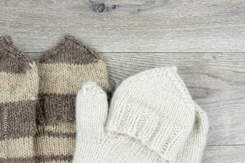 Knitted mittens on a wooden background. Mittens with a flap. The concept of hobby, home production and individual entrepreneurship.