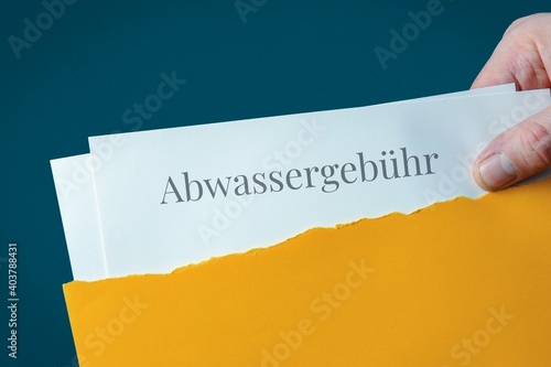 Abwassergebühr. Briefumschlag wird geöffnet. Hand entnimmt Unterlagen. Text auf Post-Brief.