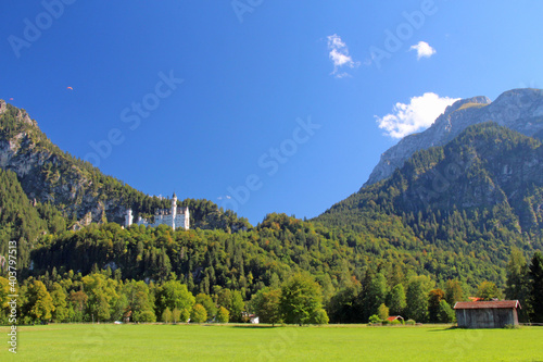 Deutsches Märchen Schloss Neuschwanstein in den Bergen der Alpen in Deutschland Europa an einem sonnigen Tag mit blauem Himmel, Sonne und Wolken