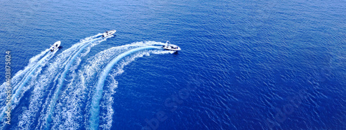 Aerial drone ultra wide top down photo of synchronised powerboats cruising in high speed in deep blue open ocean sea