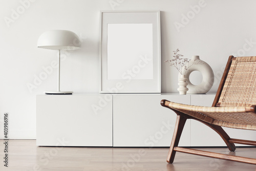 Blank picture frame mockup on white wall. White living room design. View of modern scandinavian style interior with chair. Home staging and minimalism concept