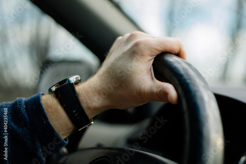 Close-up of a male hand on steering wheel in a modern car in the UK steering wheel on the right