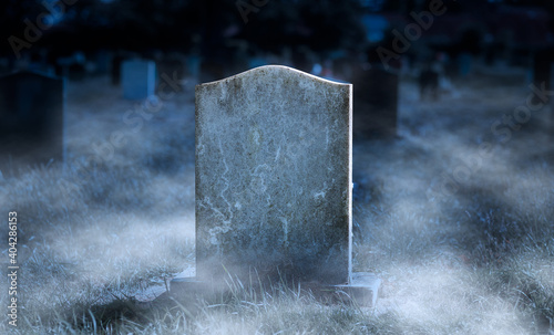 Creepy blank gravestone in graveyard at night with low spooky fog