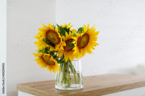 Beautiful yellow sunflowers on wooden table in room