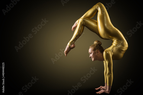 Flexible Woman Gymnast doing Yoga Stretching Pose. Standing on hands Back bending. Gold perfect strong healthy Acrobat Body. Over Black