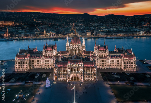 Budapest, Hungary - Aerial panoramic view of the beautiful illuminated Hungarian Parliament building at blue hour with Christmas tree. Buda Hills and River Danube at background on a December evening