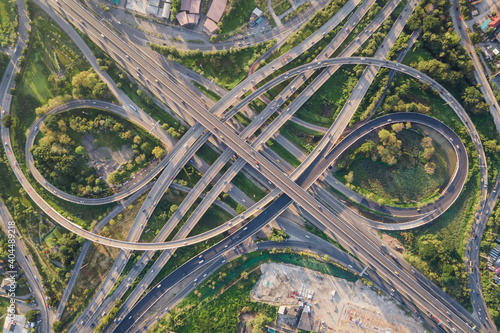 Aerial view of road interchange or highway intersection with busy urban traffic speeding on the road. Junction network of transportation taken by drone.