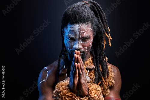 black male model doing ritual isolated over black background, portrait of man in national wear on naked body, tribal maya aborigen, shaman