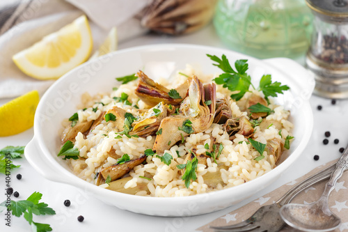 Italian risotto with artichokes and fresh parsley served on a white plate