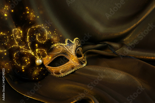 Photo of elegant and delicate gold Venetian mask over dark silk background