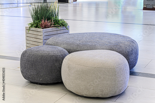 Sitting area in lobby, large shopping center - round ottoman fabric and artificial plants as decoration. Decoration of trading floors, exhibitions, recreation islands in public places.