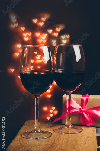 Two red wine glasses on a parkling heart shape backdrop