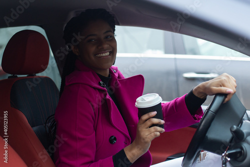 beautiful african american woman in car with coffee