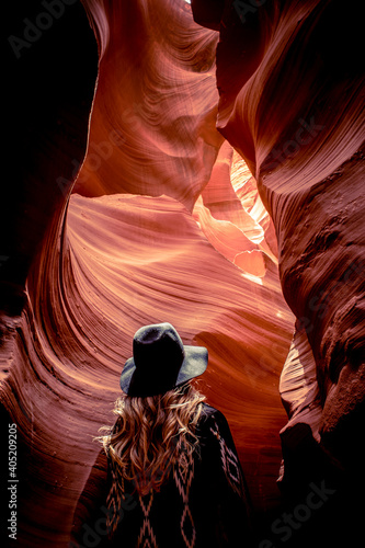 A woman looks up at the red sandstone textures of Antelope Canyon, the most-visited and most photographed slot canyon in the American Southwest located on Navajo land near Page, Arizona, USA. 