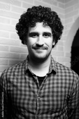 Black and white monochrome portrait of a red curly haired man with a mustache who looks like the scientist Einstein.