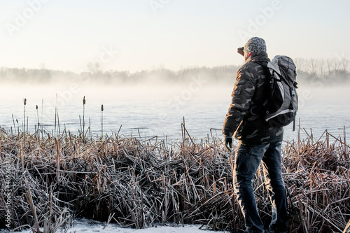 Samotny mężczyzna na brzegu jeziora zimą