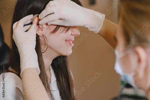 Woman assumes hearing aid. The choice of hearing aid hearing care professional.
