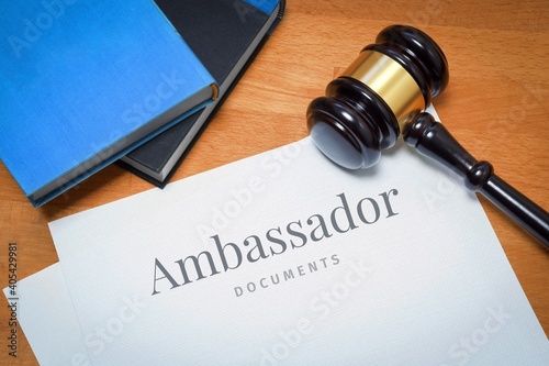 Ambassador. Document with label. Desk with books and judges gavel in a lawyer's office.