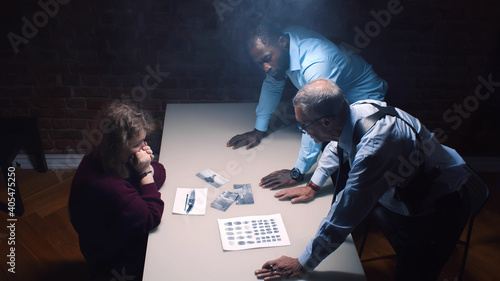 Two police officers and woman criminal in interrogation room