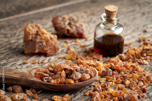 Myrrh resin on a spoon, with myrrh essential oil in the background