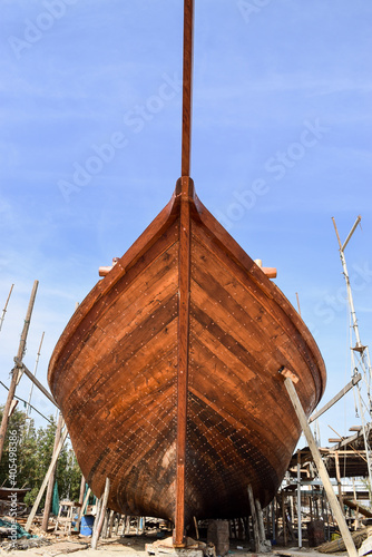 Frontal view of a wooden dhow (a traditional arabian sailing vessel) being constructed in Sur Dhow Factory. Sur, Oman.