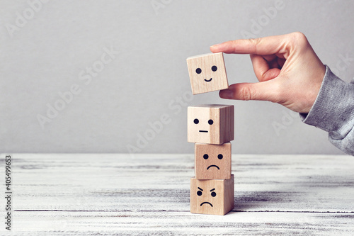 Wooden cubes with drawings of different emotions: sadness, anger, calmness, joy. Choosing joy in life 