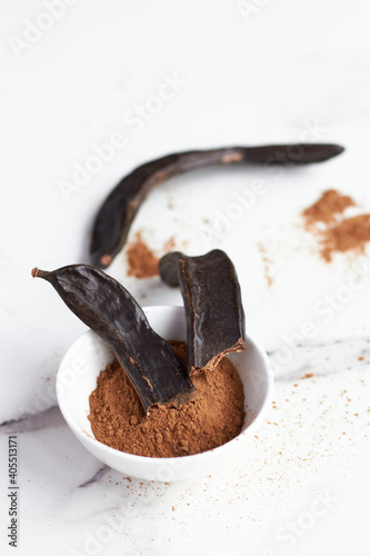 white bowl with carob powder and been in a white surface