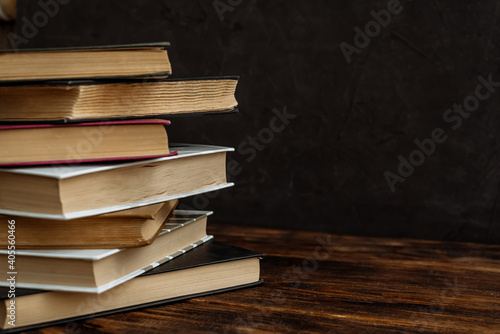 a stack of hardcover books on a dark background copy space