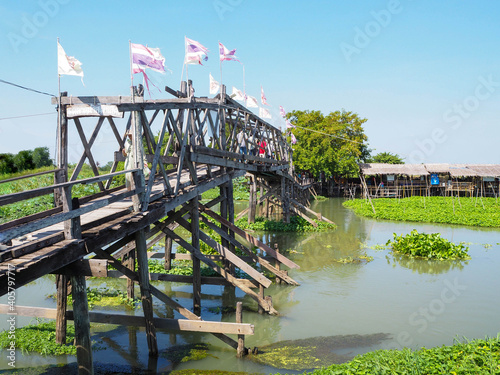 The good view of 100 Years wooden Bridge of Riverside community and floating market,Tha Chin River, Thailand