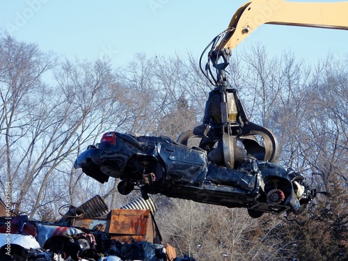 Junkyard crane with claw moving crushed car