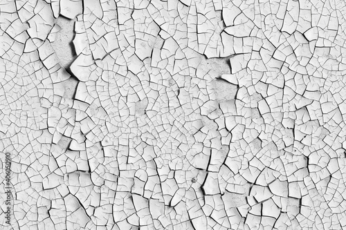 White peeling paint on the wall. Old concrete wall with cracked flaking paint. Weathered rough painted surface with patterns of cracks and peeling. High resolution texture for background and design.