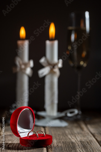 champagne and two white wedding candles with wedding rings