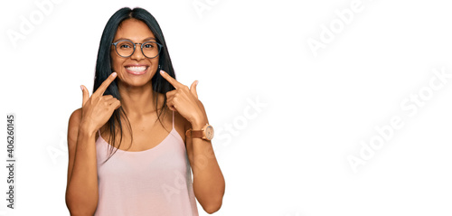 Young african american woman wearing casual clothes and glasses smiling with open mouth, fingers pointing and forcing cheerful smile