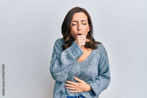 Young brunette woman wearing casual winter sweater feeling unwell and coughing as symptom for cold or bronchitis. health care concept.