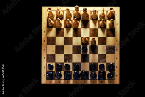 Retro chess board with figures from USSR on a black background. Chess opening Queen Gambit, top view