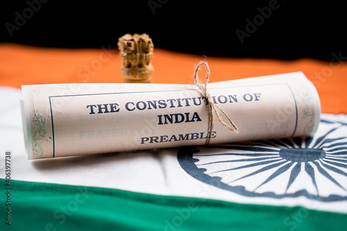 Indian constitution or Bharatiya Savidhana preamble old scattered text paper placed on Indian flag - Concept of Freedom, Nationality and patriotism.