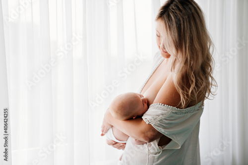 mom feeds baby standing at the window. breast-feeding.