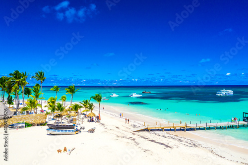 Aerial drone view of beautiful atlantic tropical beach with palms, straw umbrellas and boats. Bavaro, Punta Cana, Dominican Republic. Vacation background.