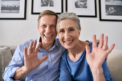 Happy senior couple greeting family making online video call talking to web cam. Middle aged old grandparents waving hands enjoying virtual distance meeting chat looking at camera at home, webcam view