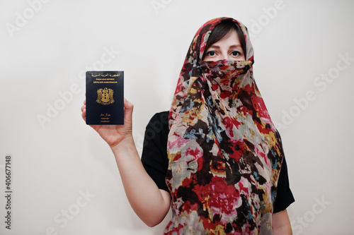 Young arabian muslim woman in hijab clothes hold Syrian Arab Republic passport on white wall background, studio portrait.