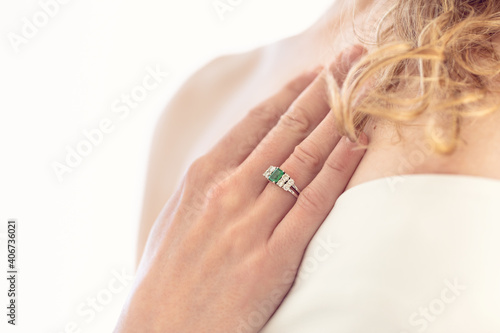 Detalle de novia llevando anillo de compromiso de esmeralda y diamantes