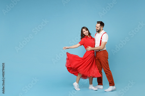 Full length of funny young couple two friends man woman in white red clothes hugging dancing having fun isolated on pastel blue color background studio portrait. St. Valentine's Day holiday concept.