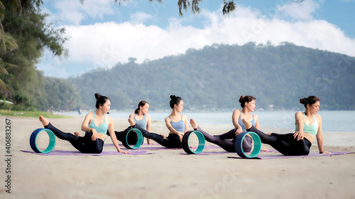 Five people practicing yoga at the beach .