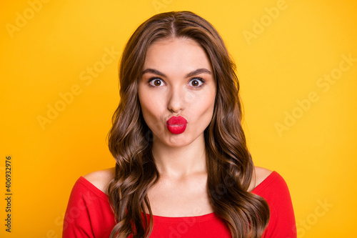 Photo portrait of funky brunette sending air kiss in red top isolated on vivid yellow color background